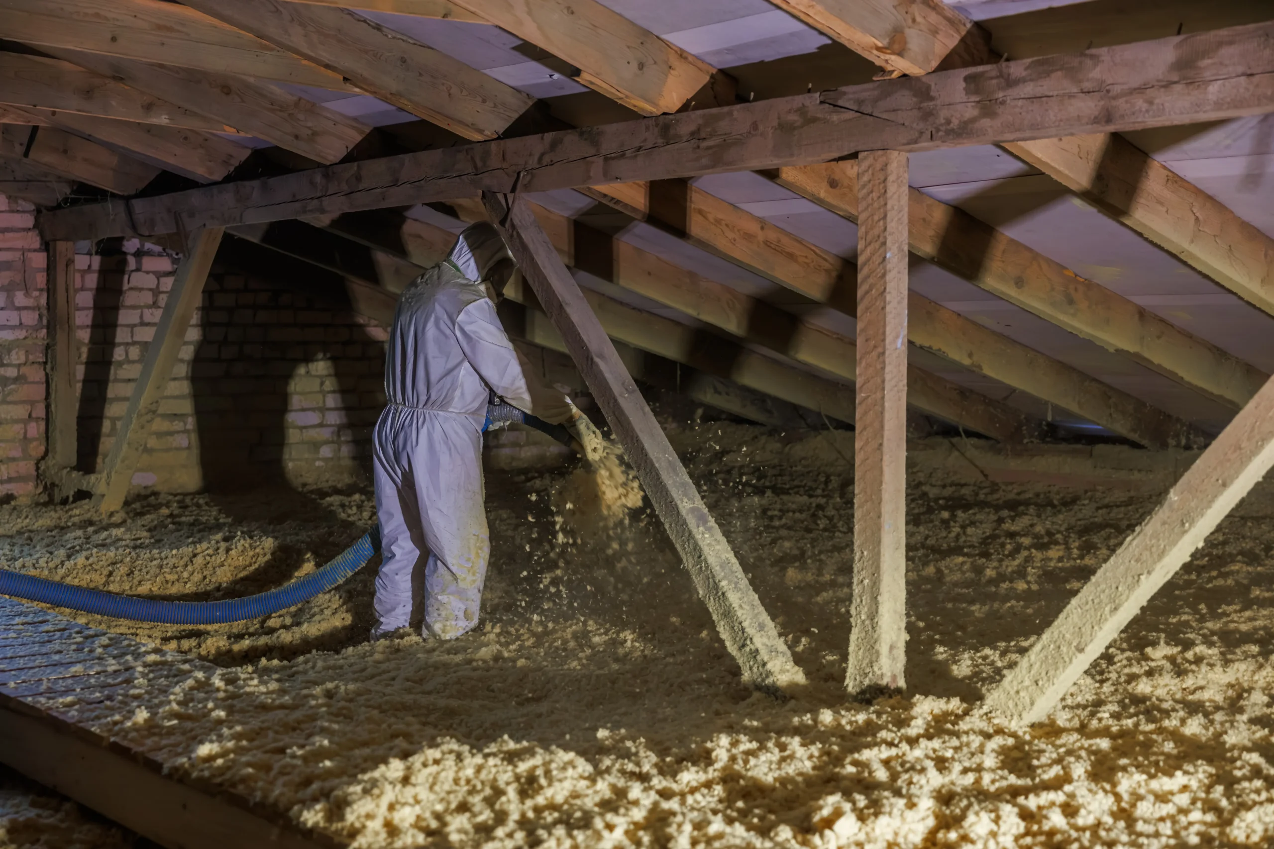 A technician installing blown in attic insulation.